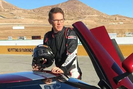 Randy Pobst in his race suit beside a red sports car